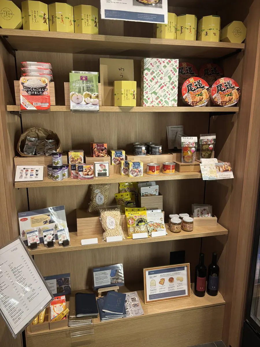 フェアフィールド広島世羅の売店の棚。パックご飯、尾道ラーメンのカップ麺、レトルトカレー、缶詰、ピクルス、地元の焼き菓子などが並ぶ