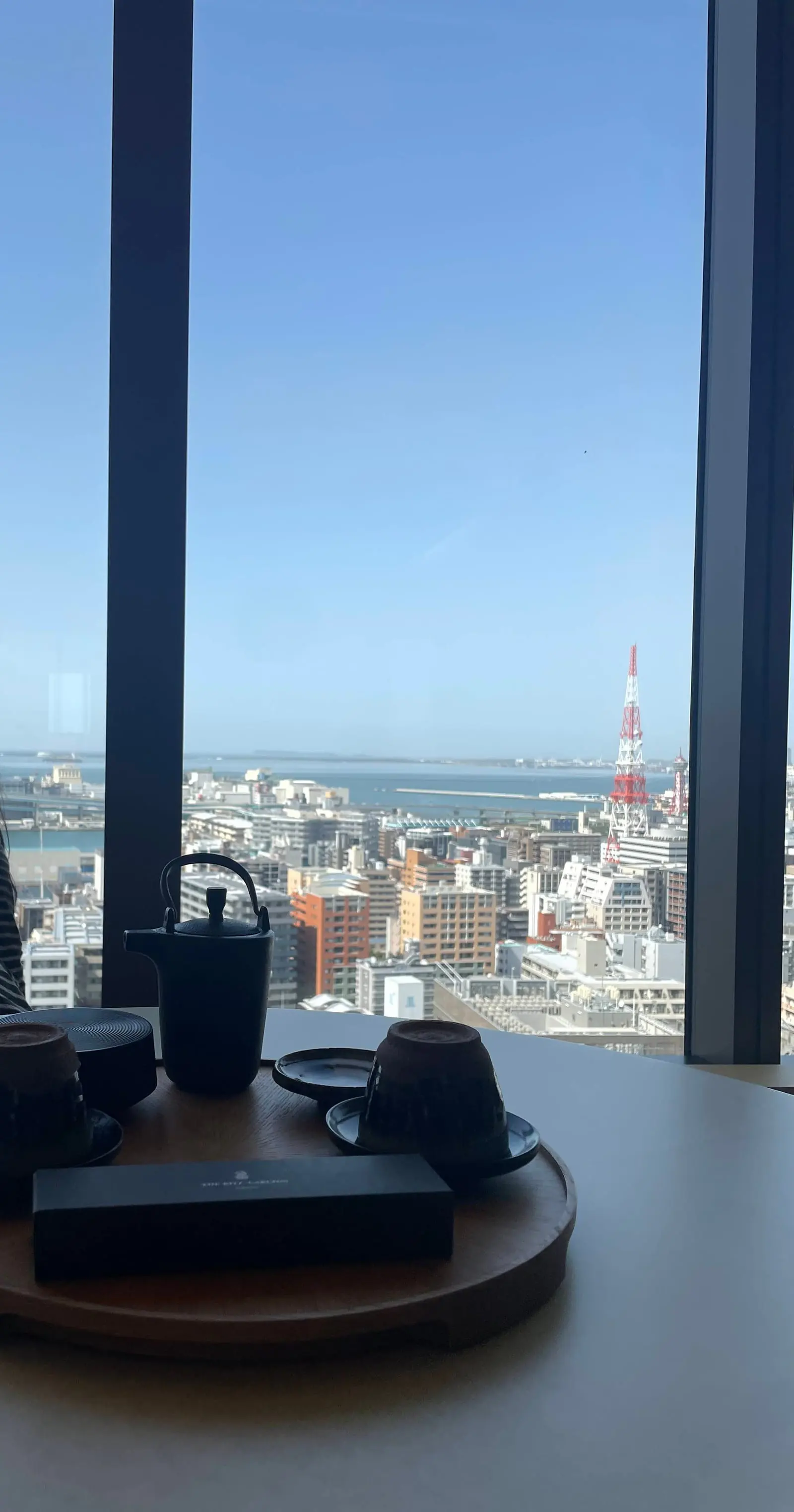 客室の窓から見た福岡の街並み。ビル群の向こうに博多湾と福岡タワーが見える