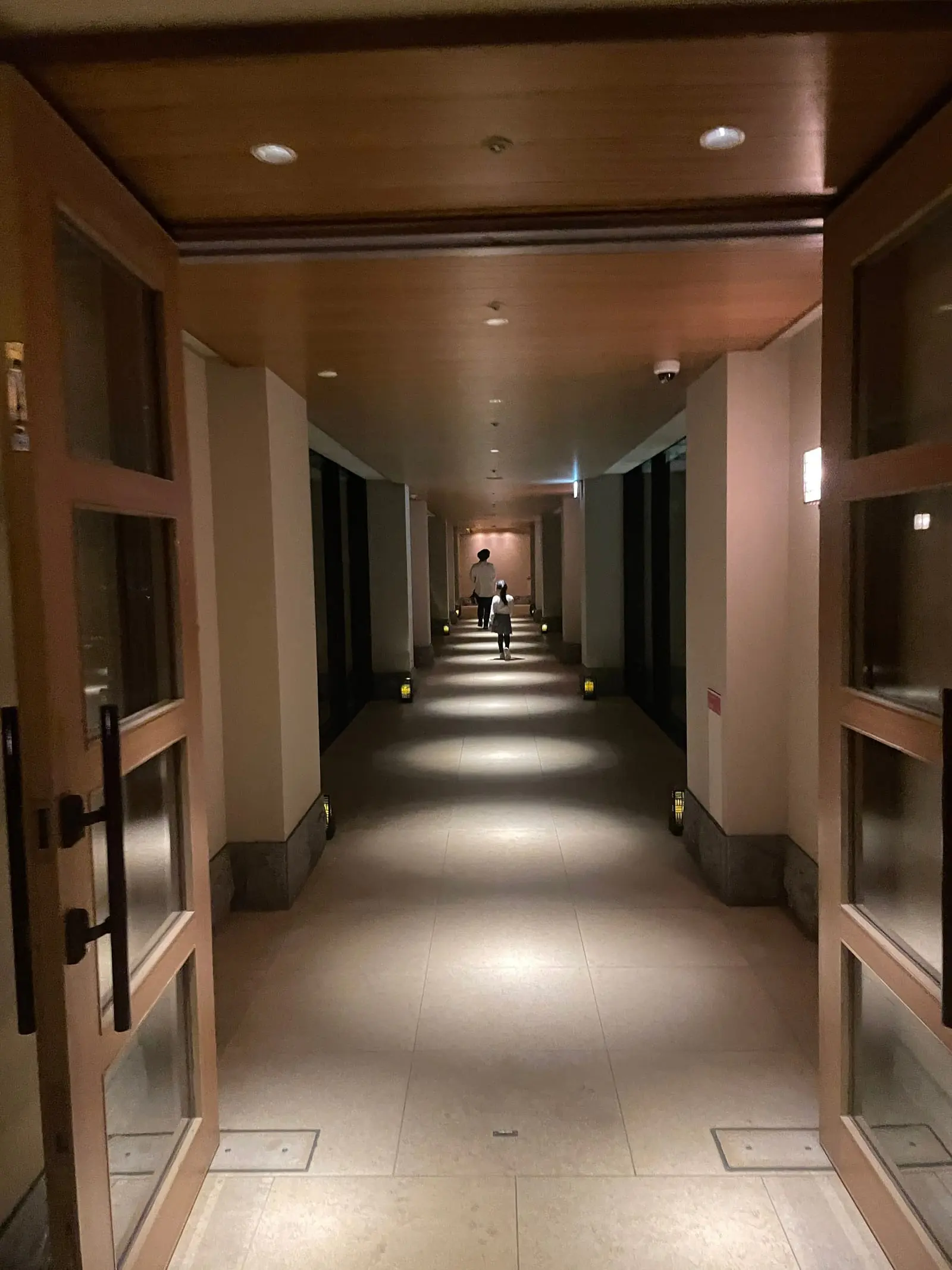 客室へ続く長い廊下。足元と天井の照明が抑えられた明るさで続いている