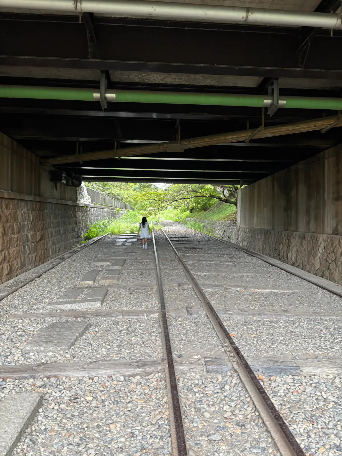 蹴上インクラインの廃線跡。砂利に敷かれた2本のレールが、道路の下をくぐるトンネルへ向かって伸びている